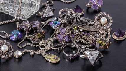 Beautiful silver jewelry with emeralds and amethysts on a black leather background. 