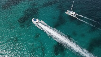 Bote y catamaran en playa cristalina azul tomada desde un Drone