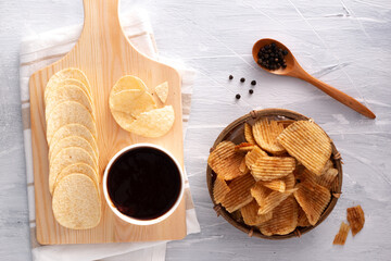 Original flavour potato chips and black pepper flavour chips with barbecue sauce and black pepper seeds on the wooden spoon