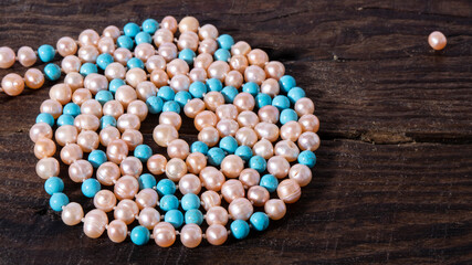 Beautiful bluish-green turquoise beads and iridescent pearl necklace on a wooden old surface....