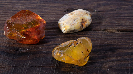 Different Baltic amber stones on a wooden background. Energy mineral. Material for jewelers. Alternative medicine.