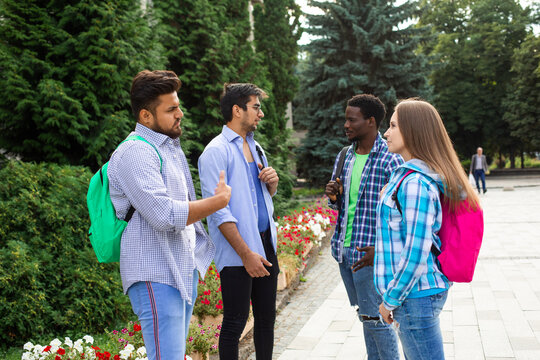 Group of studens stand with backpacks at the campus and discuss lessons