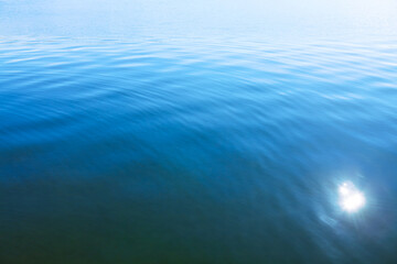 Blue water surface with sun glowing reflection