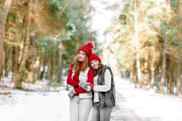 Two happy young women in snow, winter nature background.