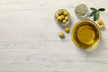 Glass bowl with fresh olive oil on white wooden table, flat lay. Space for text