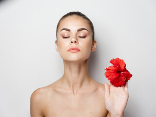 Fototapeta na wymiar attractive woman with bare shoulders holding a red flower in her hand 