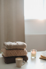 cozy comfortable home autumn still life with a candle, book, knitted sweaters and plaid