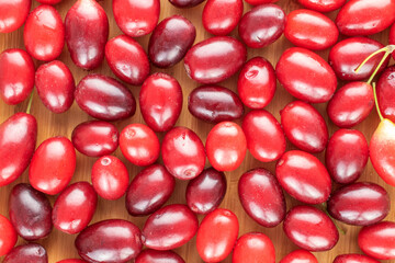 Several bright red ripe dogwood berries  on a wooden table, close-up, top view.