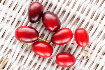 Several bright red ripe dogwood berries on a vine mat, close-up, top view.