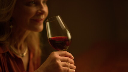 Old aged woman drinking red wine glass indoor. Rich retirement lifestyle concept