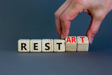 Rest and restart symbol. Businessman turns wooden cubes and changes the word 'rest' to 'restart'. Beautiful grey background, copy space. Business, rest and restart concept.