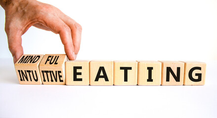Mindful or intuitive eating symbol. Doctor turns cubes and changes words intuitive eating to mindful eating. Beautiful white background, copy space. Medical and mindful or intuitive eating concept.