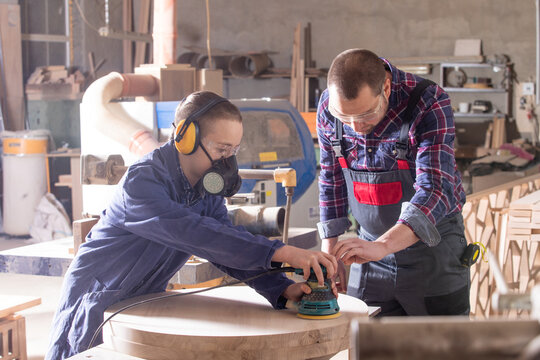 Experienced carpenter teaching young apprentice at workshop