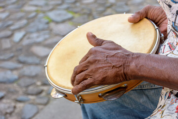 Brazilian samba performance with musician playing tambourine in the streets of Pelourinho, city of Salvador, Bahia - obrazy, fototapety, plakaty