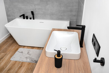 A modern washbasin in the bathroom in a wall mounted cupboard with a matte black faucet, a wall...
