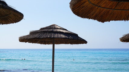 straw umbrellas from the sun on the background of blue sky and sea summer beach vacation