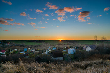 sunset over dacha and farm field