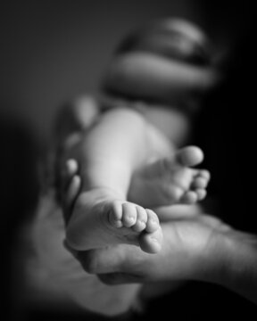 Baby feet in mother's hands. The feet of the little newborn baby on the female stamped hands, close-up, selective focus. Mom and her child. Beautiful conceptual image of motherhood