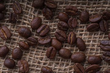 Fragrant coffee beans are randomly scattered on coarse burlap