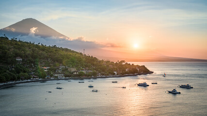 Landscape of Bali island north coastline at sunset, with Mount Agung volcano peak and forest slopes, and Java sea, from hilltop near Amed, Bali, Indonesia