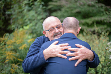 Naklejka na ściany i meble A married, elderly gay male couple embrace each other in a show of love and affection.