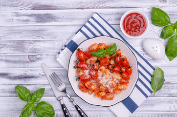 Gnocchi with tomatoes, red sauce, cheese and basil leaves