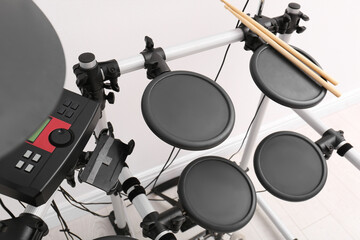 Modern electronic drum kit near white wall indoors. Musical instrument