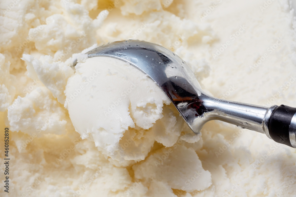 Sticker Closeup shot of a metal scoop spoon with a ball of cold white vanilla ice cream