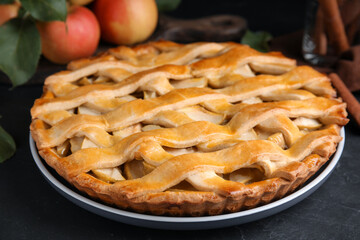 Delicious traditional apple pie on black table, closeup