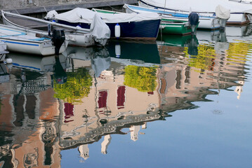 Fototapeta na wymiar Villaggio e barche riflessi sul lago di Garda