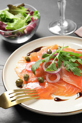 Delicious salmon carpaccio served on black table, closeup