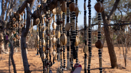 Close up of strings of African necklaces made from beads and seeds on display at an outdoor market...