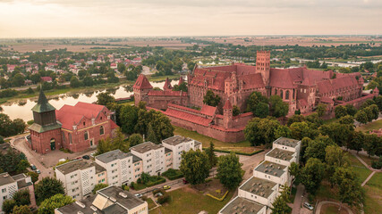 Fototapeta na wymiar Malbork,Poland. Aerial photo from drone to Medieval Malbork ( Zamek w Maborku, Ordensburg Marienburg ),castle in Poland fortress of the Teutonic Knights at the Nogat river in sunset light.(Series