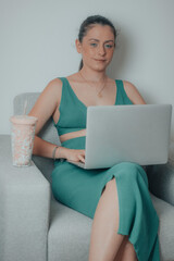 Secretaria con vestido de una empresa sentada en el despacho de su habitación con su laptop...