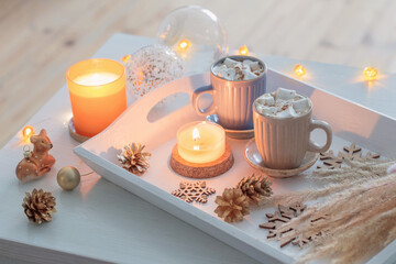 Obraz na płótnie Canvas two cups of hot drink with marshmallows and christmas decor on white wooden tray