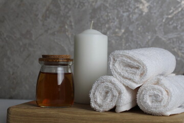 Fototapeta na wymiar oil for body massage white candle towels snail on a wooden tray on a gray background side view. Spa relaxation massage. Body care
