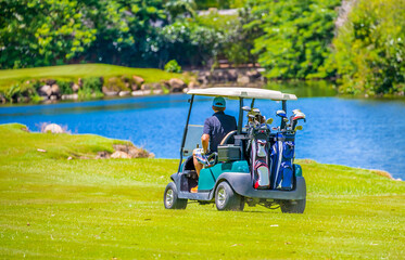 Golfers drive a golf car across a golf course in the Seychelles. Golf sport in the background of a tropical landscape.