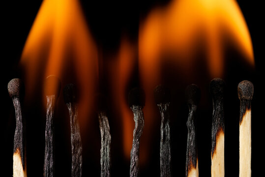 Matches in bright yellow fire, close up, on black background. Burning matchsticks turn into ashes.