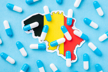 Flag of Belgium and blue and white capsules pills on top. Medical system of Belgium