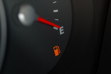 Naklejka premium Modern car fuel gauge showing empty tank. Close up view of empty fuel warning light.