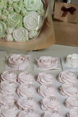 Homemade marshmallows in craft packaging. Zephyr in the form of a rose. Against the background of pine boards.