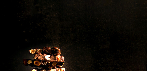 Chocolate with nuts on dark background. World Chocolate Day or happiness is in small things. Close-up