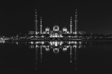 Naklejka premium Famous Grand Mosque in Abu Dhabi, United Arab Emirates at night with a reflection in the pool in black and white