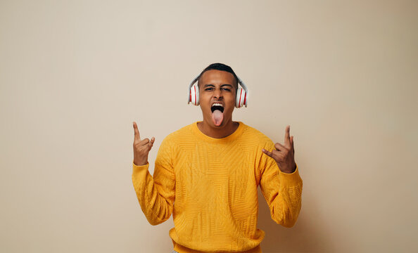 Young Latinx Man With Headset Listen Music Making Sign Rock Metal With The Fingers.