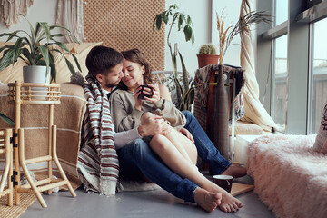 Loving couple sitting together and look at window. Girl drinking tea.