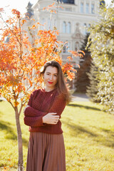 Beautiful woman in burgundy sweater walking in autumn park