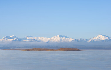 snowbound mountain chain beyond frozen lake at bright winter day