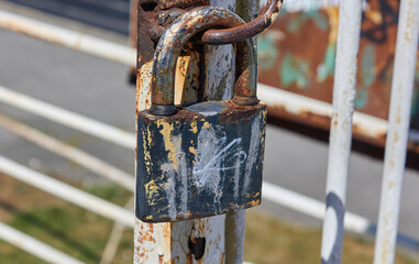 Rusty old padlock. Close up of locked metal gate. 