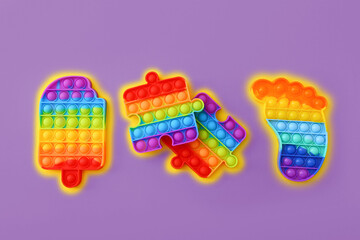 Colorful Push Pop It Bubble Sensory Fidget Toys of different shapes on purple background, top view