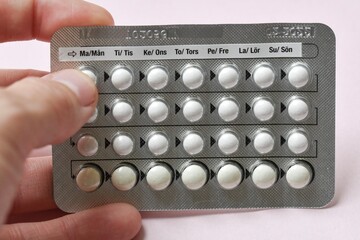 A woman holding full chart of birth control pills